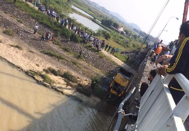 Tại hiện trường vụ việc, hàng chục mét thành cầu đã bị hư hỏng do vụ tai nạn. Rất đông người dân hiếu kỳ đứng theo dõi vụ tai nạn hi hữu trên.