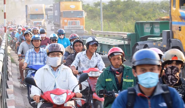 Xe máy chen chúc giữa dòng xe tải để cố thoát ra thảm cảnh kẹt xe.