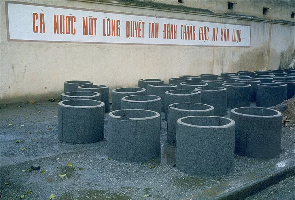 Khẩu hiệu "Cả nước một lòng quyết tâm đánh thắng giặc Mỹ xâm lược" trên bức tưởng phía ngoài xưởng sản xuất ống bê tông.