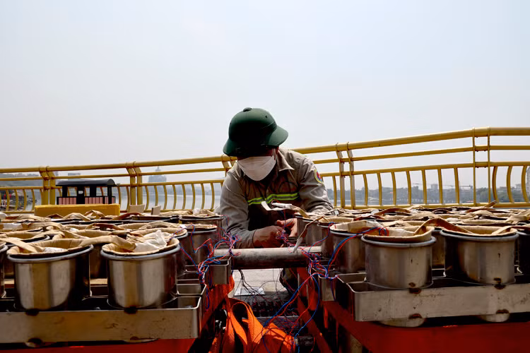 Nhân viên kỹ thuật kết nối dây từng thùng với bảng điều khiển một cách cẩn thận.