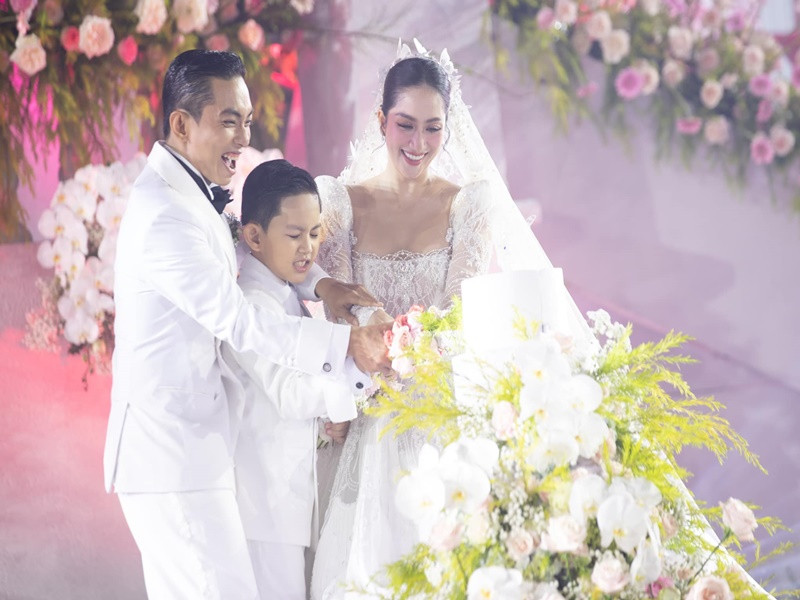 Cặp đôi cùng con trai thực hiện nghi lễ cắt bánh cưới.