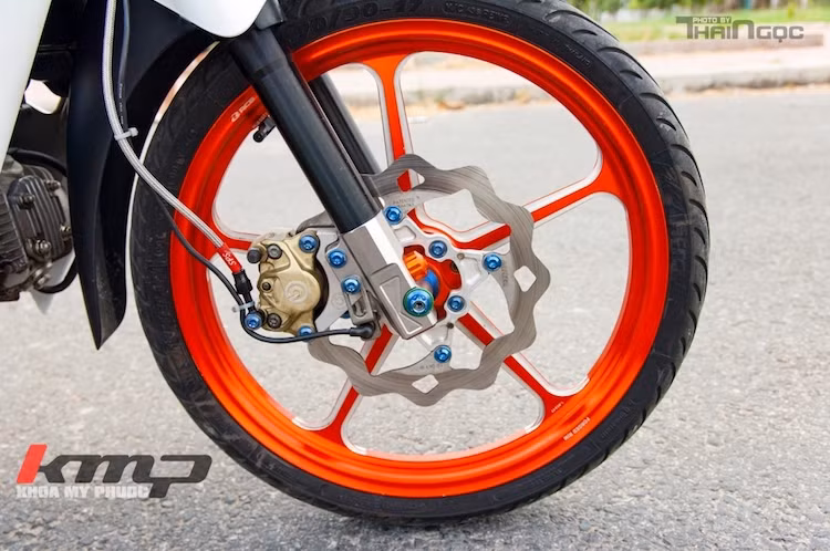 Trong đó, chi tiết mang tính quyết định tới vẻ ngoài của chiếc xe là cặp mâm 5 cây Racing Boy CNC sắc sảo và nổi bật với màu cam. Bên cạnh đó, phuộc trước nguyên bản của Wave Alpha đã được độ chân phuộc CNC, đồng thời hệ thống phanh cũng được nâng cấp với đĩa Galfer lòng nhôm CNC và heo Brembo 2 pis đối xứng.