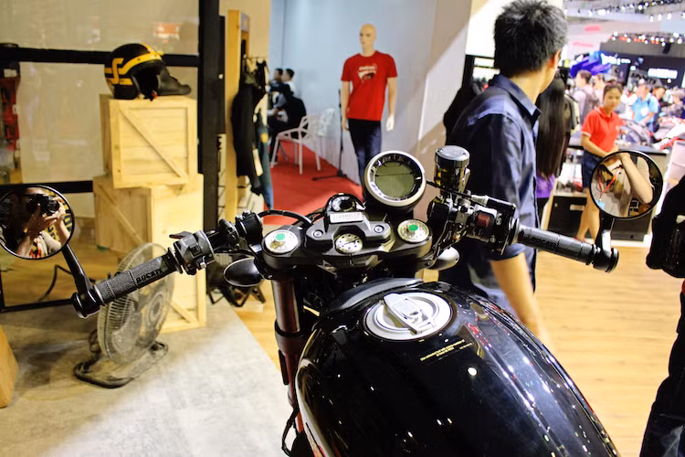 Theo đúng phong cách cafe racer, Scrambler Cafe Racer được trang bị cặp tay lái clip-on thể thao, với 2 đầu tay lái là cặp gương hậu gắn gù gọn gàng. Để che đi lỗ bắt gù ghi-đông trên chảng ba, Ducati đã sử dụng một tấm thép với bảng tên Scrambler khá đẹp mắt. Đồng hồ điện tử tròn của xe hoàn toàn không có thay đổi so với các bản Scrambler khác.