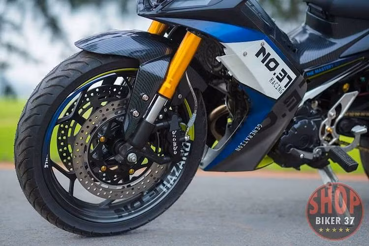 "Dàn chân" nguyên bản của Exciter đã được độ lại khá "khủng", với cặp phuộc ống lồng nguyên bản thay bằng phuộc USD từ xe phân khối lớn cắt ngắn. Bánh trước của xe sử dụng mâm độ của Ninja 300 với khả năng bắt đĩa phanh 2 bên, đi kèm với cặp đĩa lớn và heo Tokico từ Honda CBR1000RR nhưng được khắc logo Brembo.