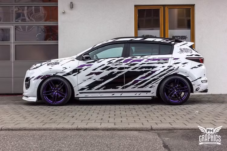 Tuy nhiên, chi tiết ấn tượng ngay từ cái nhìn đầu tiên trên bản độ Sportage này lại là thân xe được dán lớp decal màu đen trang trí độc đáo trên nền sơn trắng. Do hãng PM Graphics tại Đức thiết kế, decal dán thân xe mô phỏng những vảy bùn đất bắn lên một chiếc xe offroad và có phần khá giống như decal của mẫu bán tải Ford Raptor từ Mỹ.