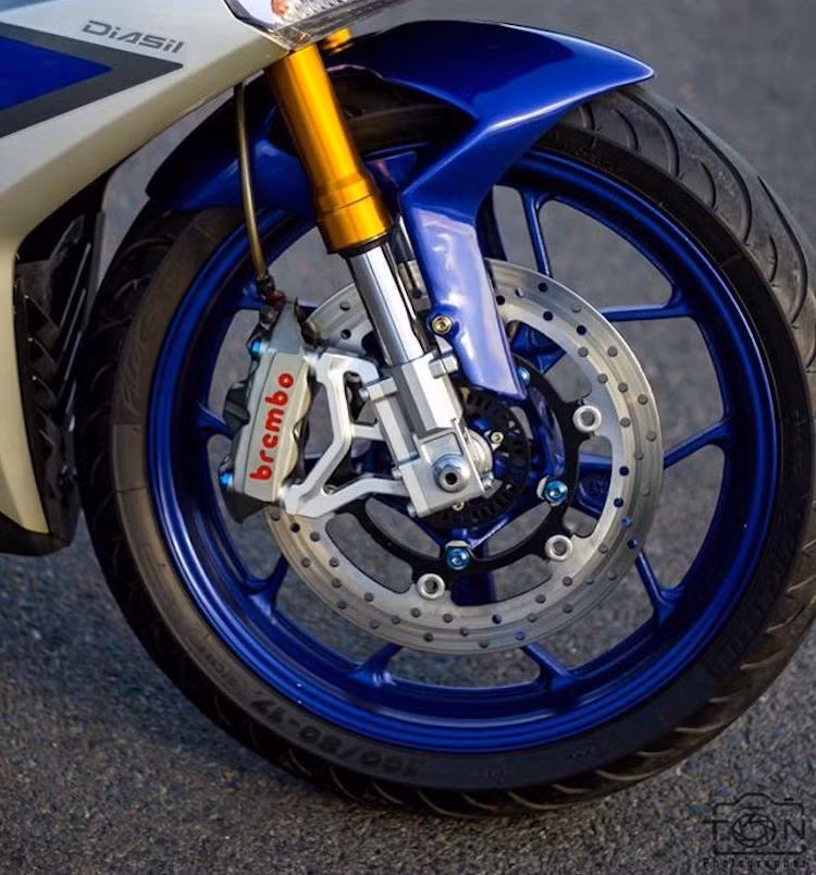 Thay vì mâm 5 cánh kép nguyên bản, chủ xe đã lựa chọn bộ mâm 5 cánh chữ Y từ chiếc sportbike Yamaha R3 cho chiếc xe. Đi kèm với mâm trước là lốp Michelin Pilot Street bản 100/80/17. Cặp phuộc nguyên bản của Exciter được thay bằng phuộc USD trông cứng cáp hơn, trong khi hệ thống phanh sử dụng đĩa R3 kết hợp heo Brembo M4 kèm pad CNC.