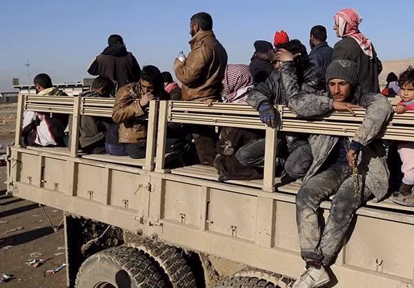 Những nam giới người Iraq ngồi sau xe tải để đưa tới nơi an toàn. Ảnh FNA