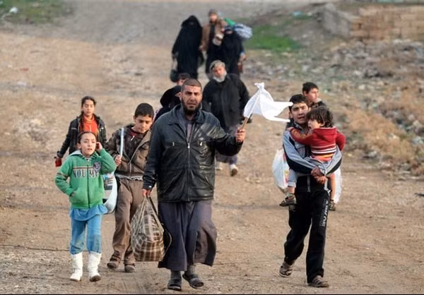 Một nhóm người dân đi bộ tới địa điểm cắm chốt của lực lượng Iraq. Ảnh FNA