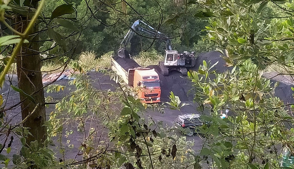 Từng gầu than đen được máy xúc chất cao lên thùng các xe tải ở điểm tập kết, sau đó vận chuyển ra khỏi mỏ.