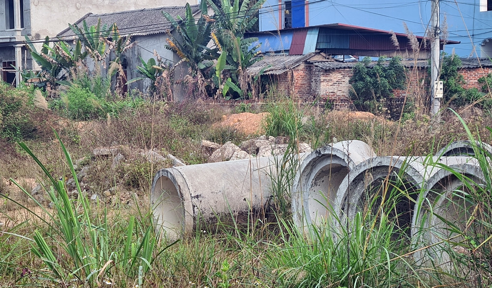 Nhiều ống cống nước được tập kết, nằm ngổn ngang lẫn với cây cỏ dại mọc bên trong khu đất dự án. Đặc biệt, theo phản ánh của người dân, đến nay dự án này vẫn vướng mắc về giải phóng mặt bằng.
