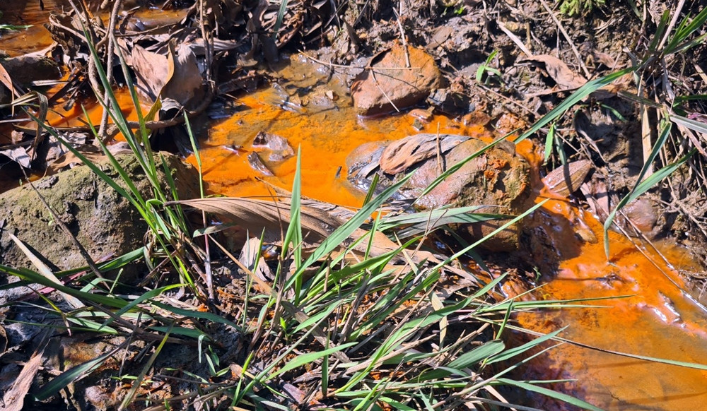 Một dòng nước gần khu vực mỏ than màu đục, đỏ đổ ra hướng suối Vọ.