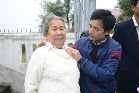 Cựu binh Lê Hữu Thảo sửa lại chiếc áo cho mẹ liệt sĩ Trần Văn Phương, người mà anh đã coi như chính là mẹ ruột của mình. Ảnh: LÊ VĂN