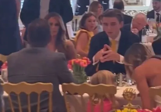 Những bức ảnh và video do khách mời dự tiệc quay lại cho thấy Barron trông lịch lãm khi mặc vest, đi giày da, đeo cà vạt màu vàng. Ảnh: Daily Mail.