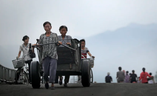 Những người phụ nữ đẩy xe và đi xe đạp qua cầu ở Hamhung, tỉnh Nam Hamgyong, Triều Tiên, ngày 21/7/2017.