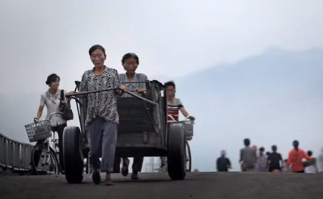 Những người phụ nữ đẩy xe và đi xe đạp qua cầu ở Hamhung, tỉnh Nam Hamgyong, Triều Tiên, ngày 21/7/2017.