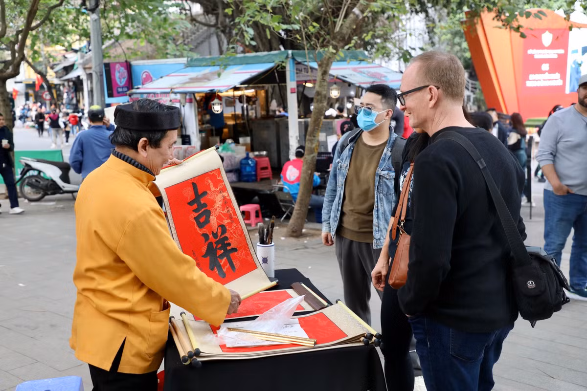 Ông đồ cho chữ du khách quốc tế trong dịp Tết Dương lịch. Không chỉ cho chữ, ông đồ còn cắt nghĩa, lý giải một số nét đẹp văn hoá của con người, phong tục Việt thời xưa.