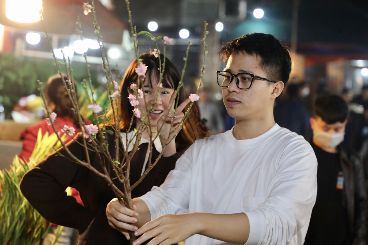 Anh Đỗ Đức Hải (Long Biên) đi cùng bạn gái là chị Nguyễn Phương Anh (Cầu Giấy) đến chợ hoa Quảng Bá vào lúc 23h đêm. Anh Hải cho biết: “Ngày cuối tuần được nghỉ và cũng là ngày cận Tết, mình và người yêu đi chợ hoa đêm để mua ít hoa về trang trí nhà ngày Tết và tiện chụp ảnh kỷ niệm luôn. Chúng mình mua cành đào này giá 80.000 đồng để chụp ảnh và sẽ mua thêm hoa tuyết mai và hoa thược dược để cắm ở nhà.”