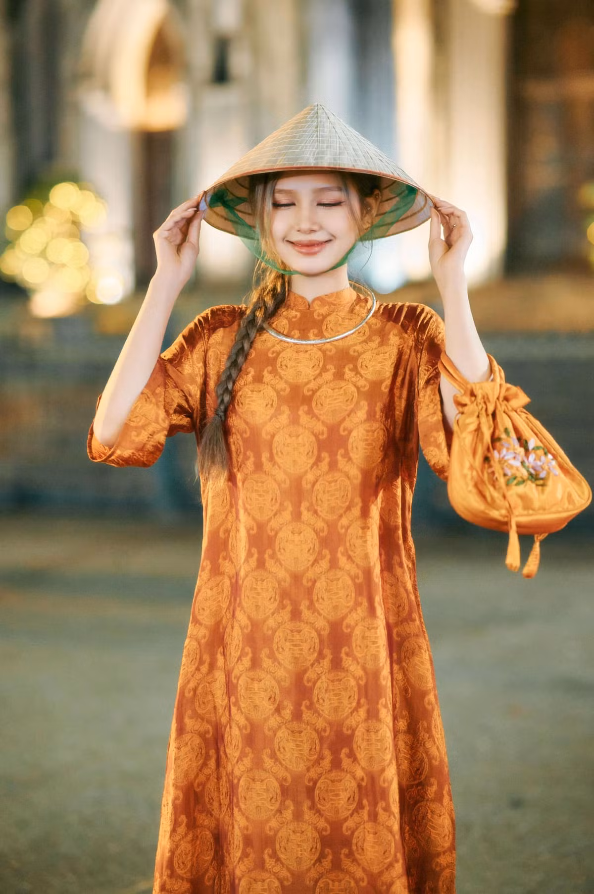 Bước vào đường đua khoe áo dài đón Tết, Xoài Non trọn màu áo cam khá nổi bật và phụ kiện là chiếc nón ná truyền thống. Tổng thể bộ outfit mang đến sự duyên dáng của nàng hot girl.