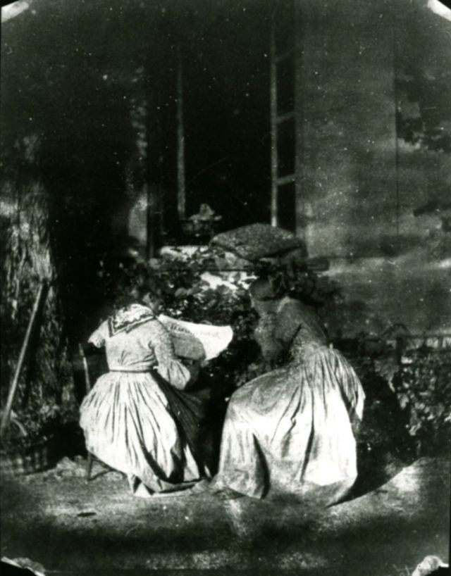 Hai phụ nữ đọc báo ở sân nhà.