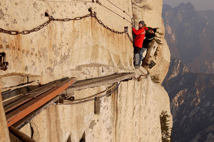 Nhiều đoạn ở đây không có gì hơn ngoài một vài tấm ván gỗ hẹp nằm vắt vẻo bên sườn núi chênh vênh, cùng một sợi xích dựng sơ sài để bám víu. Đây thực sự là thử thách "cân não" - kể cả với những du khách ưa mạo hiểm nhất. Ảnh: Blogrope.com.