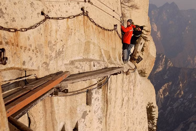 Nhiều đoạn ở đây không có gì hơn ngoài một vài tấm ván gỗ hẹp nằm vắt vẻo bên sườn núi chênh vênh, cùng một sợi xích dựng sơ sài để bám víu. Đây thực sự là thử thách "cân não" - kể cả với những du khách ưa mạo hiểm nhất. Ảnh: Blogrope.com.