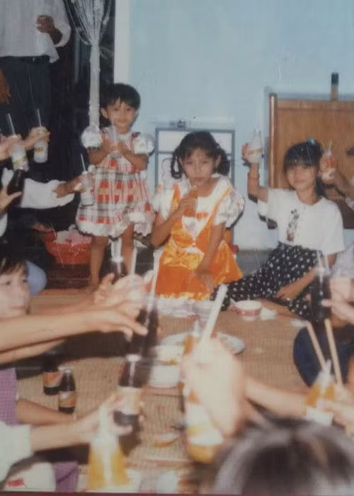 Hình ảnh hai chị em Đặng Thu Thảo (mặc váy kẻ caro, váy cam) khi còn nhỏ.