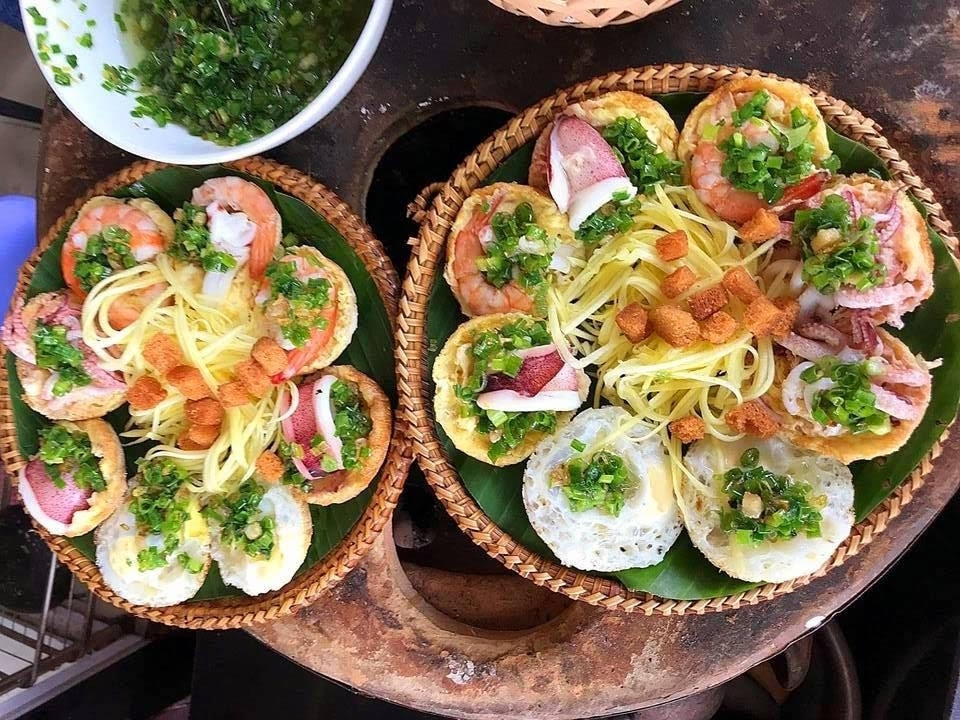 Khi no nê với hải sản tươi rói, đừng quên thưởng thức món bánh căn hải sản dân dã – một nét chấm phá mộc mạc nhưng quyến rũ. Những chiếc bánh nhỏ xinh, vàng ruộm được đổ trong khuôn đất, phủ lên nào tôm, nào mực, nào trứng, ăn kèm nước chấm đậm đà và rau sống tươi xanh, đơn giản thôi mà khiến người ta cứ xuýt xoa mãi không thôi.