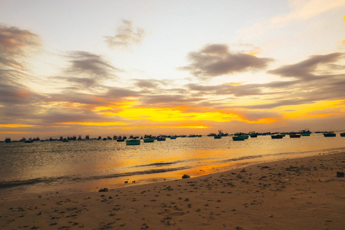 Mỗi buổi chiều, làng như khoác lên mình gam màu vàng dịu – trẻ con nô đùa bên bờ biển, người lớn loay hoay vá lưới, những chiếc thuyền nằm nghỉ chờ chuyến ra khơi tiếp theo. Mọi thứ đều chân thực, không màu mè, nhưng lại mang đến cảm giác rất đỗi gần gũi và thân quen. Ảnh Minh Hien Nguyen