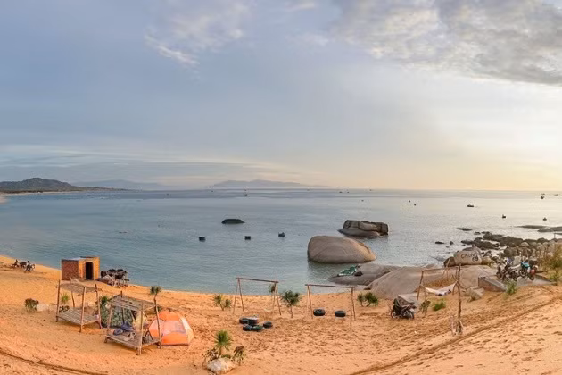 Phía sau làng chài, những dãy núi đá vôi với hình dáng kỳ thú tạo thành những bức tường đá vững chãi, bảo vệ cho ngôi làng yên bình này. Dưới ánh mặt trời, những cột đá lấp lánh ánh bạc, cùng với thảm thực vật xanh tươi tạo nên một bức tranh tuyệt đẹp, nơi núi và biển giao hòa.