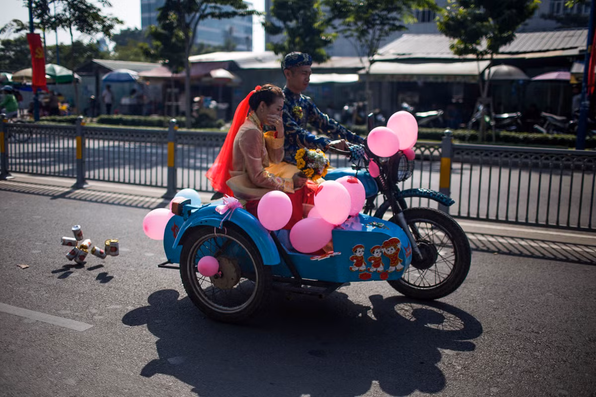 Cô dâu trẻ ngượng ngùng khi ngồi bên chú rể cùng chiếc xe hoa độc đáo.