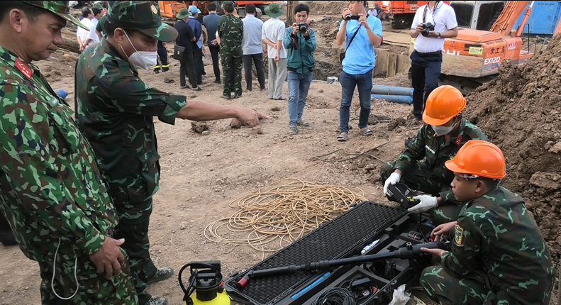 Tại hiện trường, hàng trăm người gồm lãnh đạo UBND tỉnh, huyện, đại diện các Sở, ngành cùng lực lượng cứu hộ, cứu nạn công an tỉnh Đồng Tháp, công an huyện Thanh Bình cùng lực lượng Công binh Quân khu 9 đang dùng máy khoan để làm mềm đất đá khu vực xung quanh thành ống bê tông để giảm ma sát. 