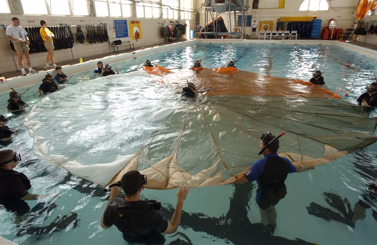 Bài tập giải cứu nạn nhân bị mắc kẹt trong dù ở dưới nước của các nhân viện cứu hộ không quân hải quân. Dù chính là kẻ thù số một của các phi công khi họ nhảy dù xuống biển, dù có thể quấn quanh người phi công khiến anh ta chết đuối nếu không giữa được bình tĩnh để thoát khỏi "mớ bòng bòng" này. Nguồn ảnh: Wiki.