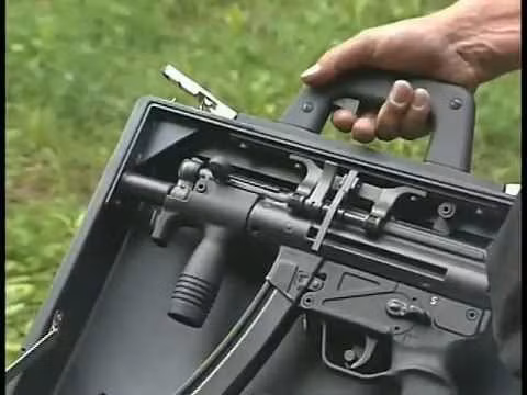 Cận cảnh bộ phận cò súng trên tai cầm của chiếc vali. Ngoài sự kín đáo, gọn nhẹ, chiếc vali này còn có nhiệm vụ chứa tất cả các vỏ đạn đã bắn ra bên trong nó, đảm bảo nhiệm vụ ám sát được diễn ra một cách bí mật vì khi không tìm thấy vỏ đạn thì lực lượng chức năng sẽ rất khó xác định được nguồn gốc của viên đạn để từ đó có thể tìm ra được quốc gia liên quan đến vụ ám sát. Nguồn ảnh: Youtube.