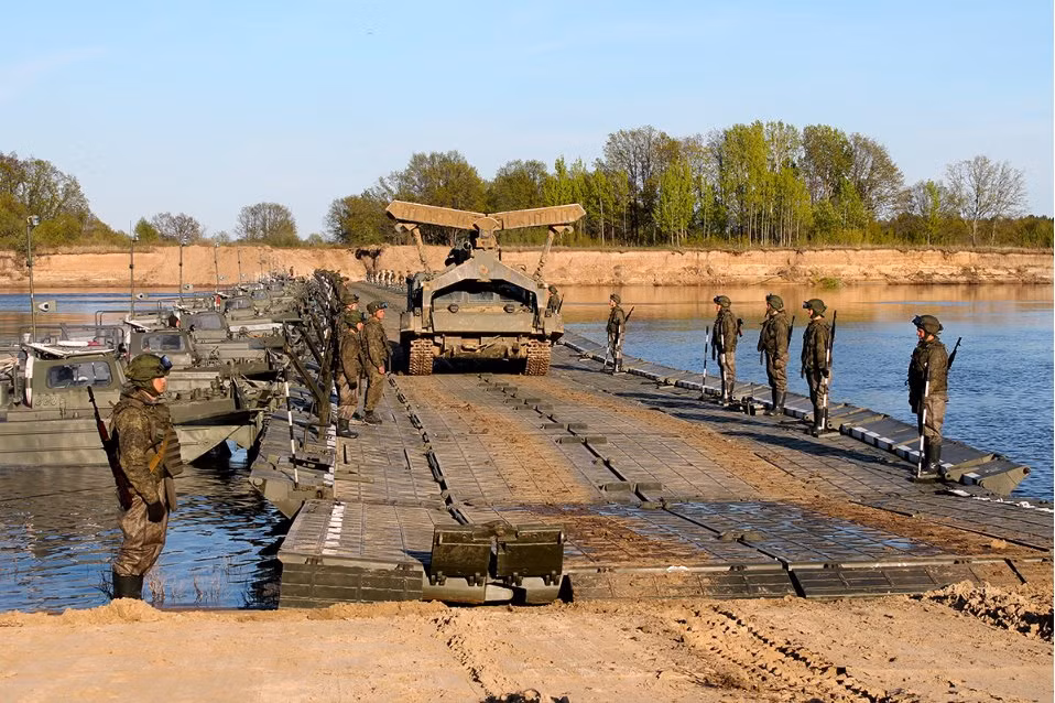 Xe công binh BAT-2 đi thử qua cầu phao, bên cạnh là các ca-nô đang đẩy cầu phao ngược hướng dòng nước để giữ cầu phao không bị trôi. Nguồn ảnh: Engmil.