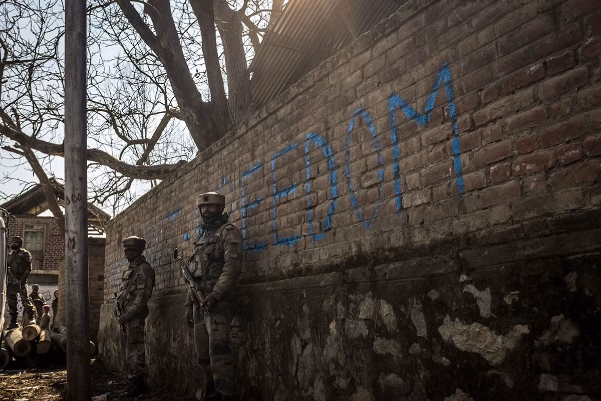 Những binh lính Ấn Độ đứng bên cạnh một bức tường ghi dòng chữ “Tự do” ở làng Panjpora, nằm ở phía nam Srinagar Ảnh: Al Jazeera.