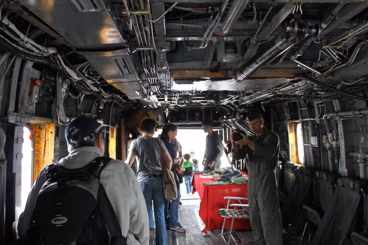 Du khách tham quan và chụp ảnh lưu niệm trong một chiếc trực thăng đậu trên boong tàu đổ bộ. Ảnh: BI.