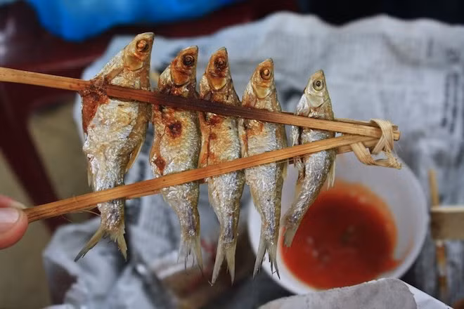 Cá nướng sông Đà: Những con cá tươi rói để nguyên con rồi dùng xiên từ đầu tới đuôi, dùng nẹp kẹp vào để cá khỏi bị rơi. Cá được nướng trên than hồng cho đến khi cháy xém, tỏa mùi thơm. Khi ăn chỉ cần rắc thêm một chút muối, rồi quấn vào trong lá chuối để một lúc là có thể ăn được. Ảnh: Danviet.