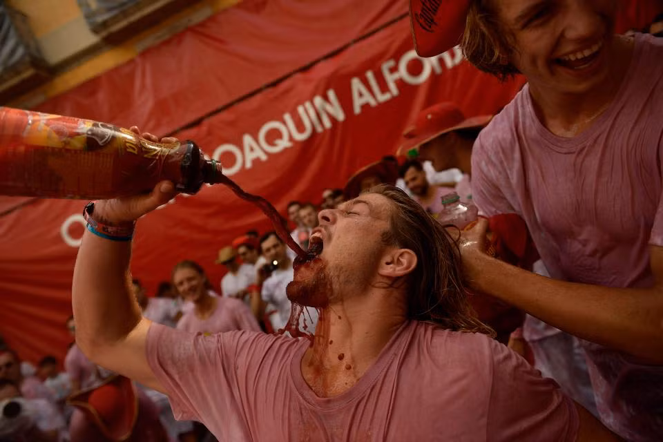 Một người đàn ông tham gia lễ hội đổ rượu vang vào miệng.