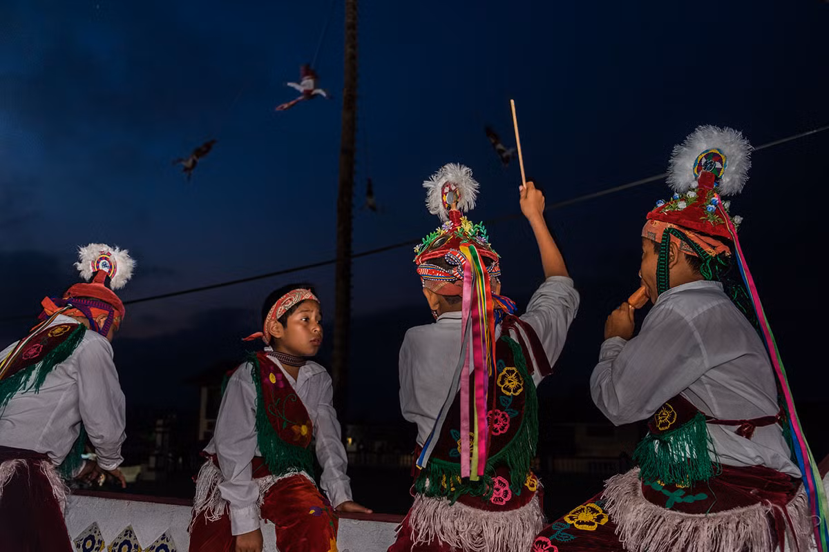 Những vũ công Voladores nhí xem những người lớn tuổi bay. Đó là ước mơ lớn nhất của các em khi tham gia học nghi lễ bay truyền thống. Ảnh: Al Jazeera.