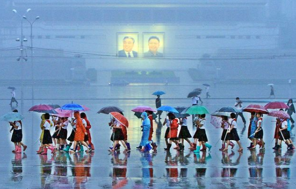 Người dân che ô đi qua khu vực Quảng trường Kim Nhật Thành.