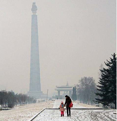 Người phụ nữ dắt con nhỏ đi trên con đường phủ đầy tuyết trắng.