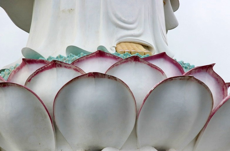 Phật Quan Âm có màu trắng đứng trên đài sen khổng lồ. Những người thợ điêu khắc cánh sen lớn màu hồng nhạt.