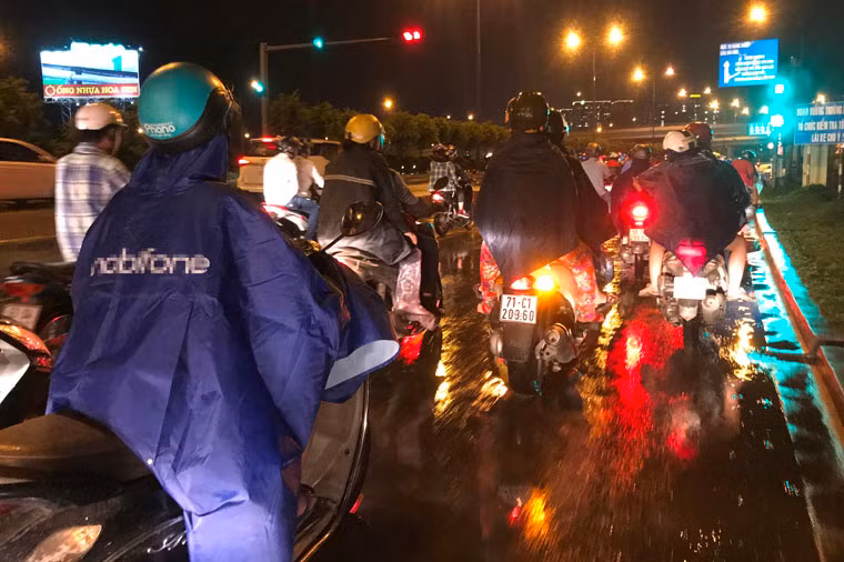 Người dân đi lại trên các tuyến đường ở Sài Gòn phải trùm kín áo mưa...