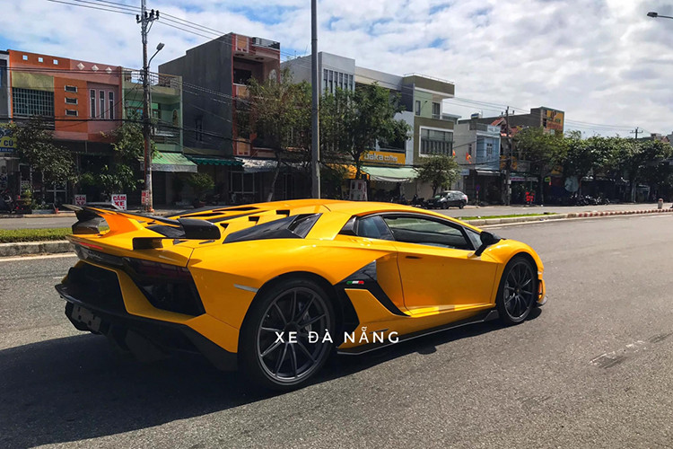 Ngoài màu sơn váng óng, chiếc siêu xe Lamborghini Aventador SVJ tại Việt Nam còn có nhiều chi tiết carbon ở cản va trước và cản va sau, ốp sườn, hốc gió bên hông hay nổi bật nhất vẫn là cánh gió đuôi carbon với điểm nhấn là hệ thống chủ động Aerodinamica Lamborghini Attiva (Ala 2.0) mới nhất của hãng xe Ý.