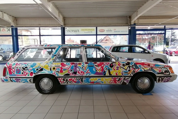 Cụ thể hơn, nó là một chiếc xe được biến đổi thành xe nghệ thuật bởi cố nghệ sĩ người Tanzania - George Lilanga trong tháng 9/1996, sau khi ông ấy đồng ý sơn thủ công cho nó để đổi lại việc ngủ vài đêm miễn phí ở một khách sạn Đức. Do đó, nó là một chiếc xe độc nhất vô nhị, và có lẽ là phương tiện 4 bánh duy nhất có mang dấu ấn của người nghệ sĩ nổi tiếng.