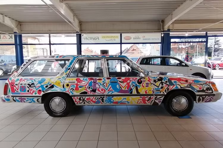 Cụ thể hơn, nó là một chiếc xe được biến đổi thành xe nghệ thuật bởi cố nghệ sĩ người Tanzania - George Lilanga trong tháng 9/1996, sau khi ông ấy đồng ý sơn thủ công cho nó để đổi lại việc ngủ vài đêm miễn phí ở một khách sạn Đức. Do đó, nó là một chiếc xe độc nhất vô nhị, và có lẽ là phương tiện 4 bánh duy nhất có mang dấu ấn của người nghệ sĩ nổi tiếng.