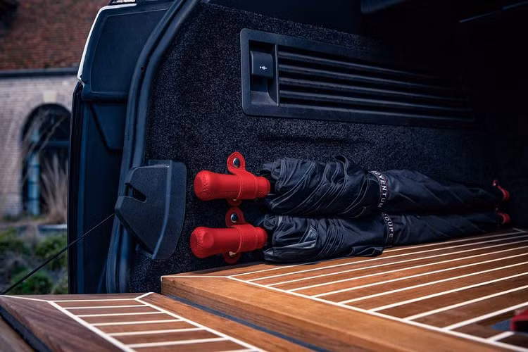 Khu vực bảng điều khiển trung tâm được sơn mài tỉ mỉ với màu đen piano trong khi khu vực sàn để chân cũng như phần cốp sau được lát gỗ sáng màu, tương phản cùng các đường kẻ vạch trắng. Đặc biệt, khách hàng mua xe còn được tặng kèm… hai chiếc ô màu đỏ - đen, được khâu thủ công bởi Niels van Roij Design.