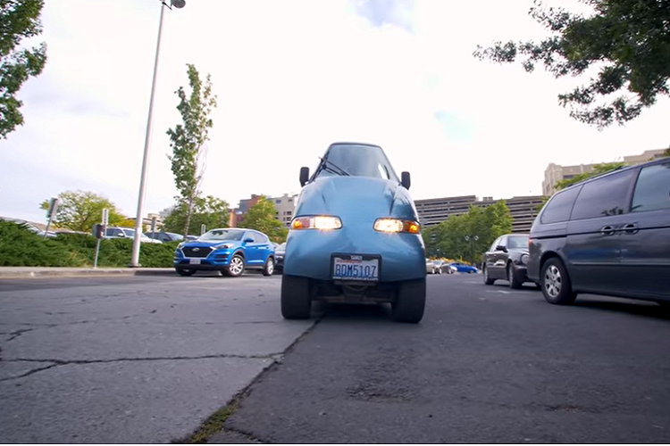 Hồi năm 1998, Rick Woodbury và con trai đã thành lập Commuter Cars ở Spokane, Washington. Phải đi làm hàng ngày bằng xe, Rick nhận ra một điều quan trọng rằng: mọi người đi làm hàng ngày bằng xe cá nhân, mà bên phía hành khách luôn để không. Cân nhắc tình trạng tắc nghẽn giao thông trên thế giới và nhận thấy ý tưởng nhân đôi số làn đường là không thể, Rick nghĩ rằng nếu chế tạo một chiếc xe chỉ chiếm một nửa không gian thì sao? Bằng cách này, người ta có thể nhồi nhét gấp 2 lần số lượng xe lên số làn đường hiện tại.