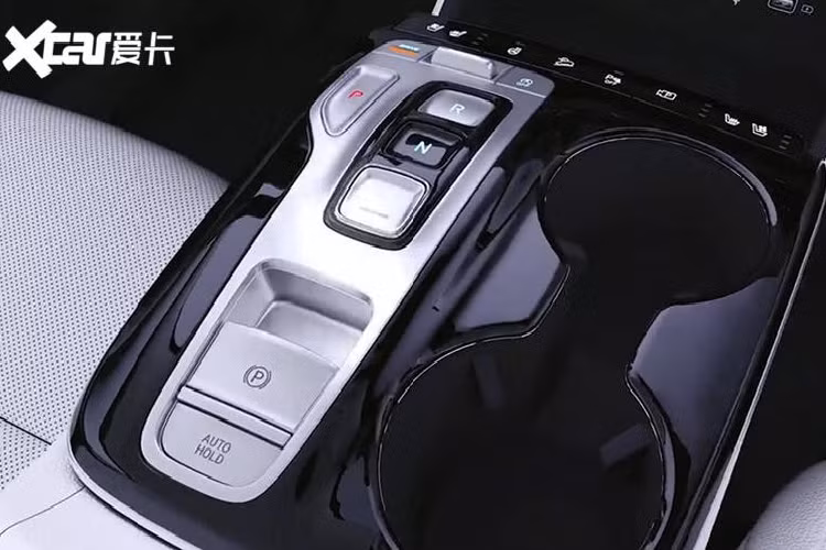 Ngay trước mặt người lái xuất hiện bảng đồng hồ kỹ thuật số và vô lăng có thiết kế đơn giản, giống loại dùng cho Hyundai Elantra mới, nhưng vẫn đi kèm đủ các phím chức năng quen thuộc. Trong khi đó, trên cụm điều khiển trung tâm xuất hiện các nút chọn số với công nghệ Shift by Wire giống đàn anh Hyundai Palisade. Tiếp đến là phanh đỗ xe điện tử, nút giữ phanh tạm thời Auto Hold và 2 ngăn đựng cốc bên cạnh.