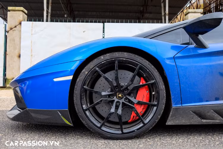 “Siêu bò” Lamborghini Aventador LP700-4 này sở hữu bộ mâm đa chấu sơn đen bóng. Ẩn phía sau là hệ thống phanh đĩa hiệu năng cao gồm cùm phanh sơn đỏ làm điểm nhấn và đĩa phanh gốm carbon có khả năng chịu nhiệt tốt. Bộ mâm có kích thước cho bánh trước/sau lần lượt là 20 và 21 inch, đi kèm với bộ lốp Pirelli P Zero được trang bị tiêu chuẩn theo xe với thông số 255/30/R20 (bánh trước) và 355/25/R21 (bánh sau), trong đó phần lốp sau của xe có kích thước gần như lớn nhất ở phân khúc siêu xe hiện nay.